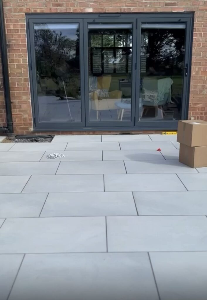 Large grey porcelain patio laid outside glazed doors by Baker Builds